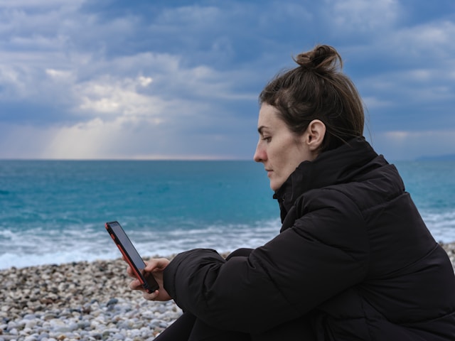 a woman scrolling on her phone on the beach
