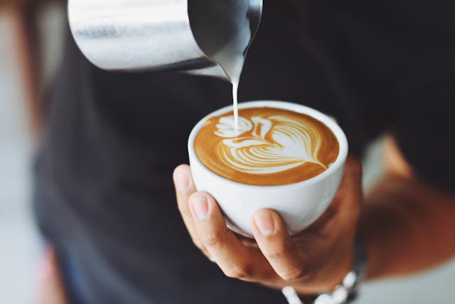 a barista making a coffee with a leaf design
