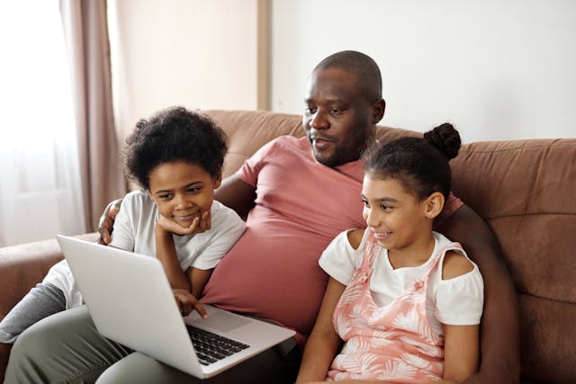 a man watching a laptop screen with his two daughter