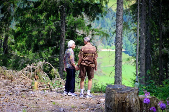 two elderly people walking in the woods
