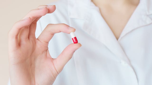 a person holding a ed and white pill in their fingetips