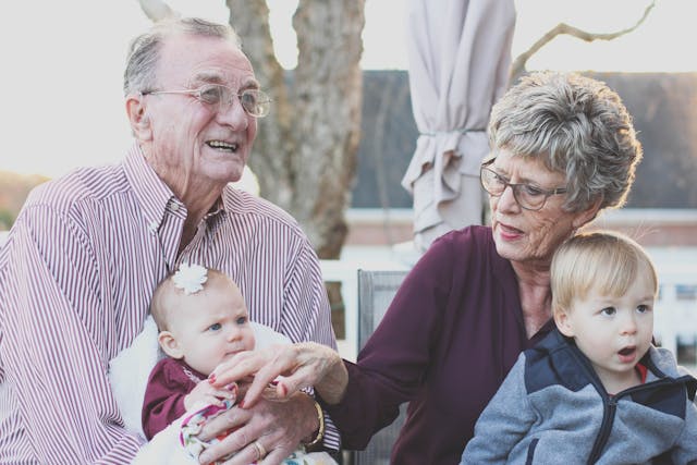 two grandparents sitting with their grandkids