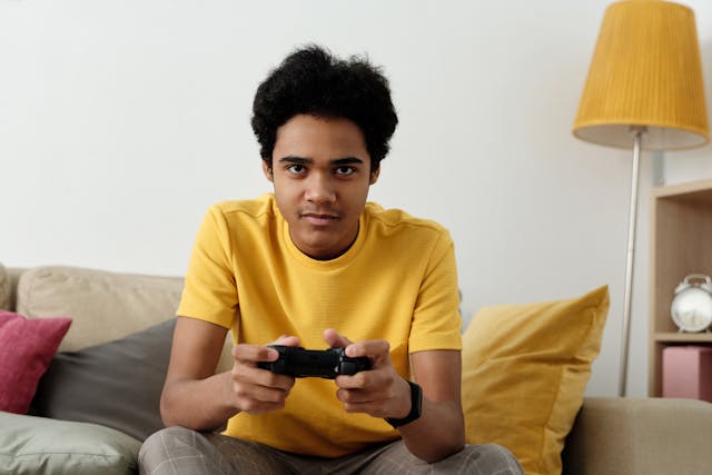a boy in a yellow shirt playing a video game