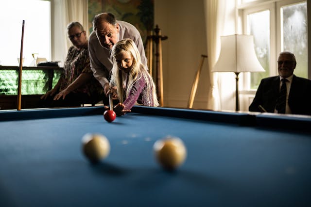 a gradfather and grandaughter playing pool