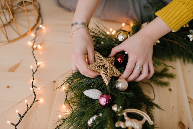a woman decorating a wreath on a table
