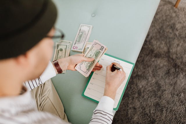 a woman counting money and notating on a notepad