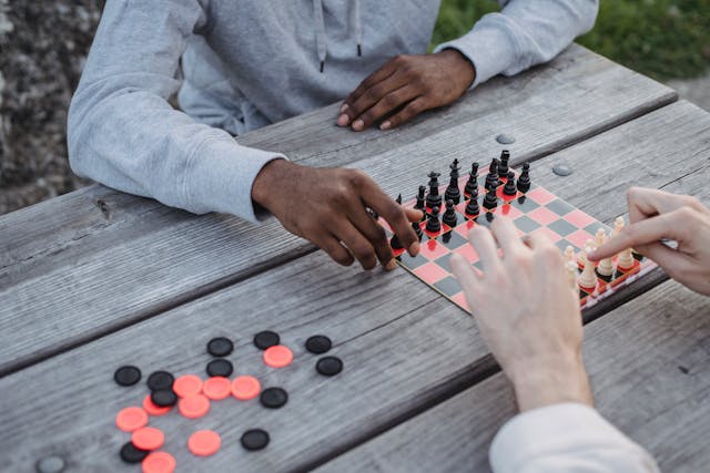 two individuals playing checkers on a picnic table