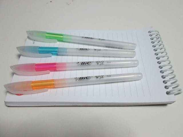 four colored pens resting on a notepad